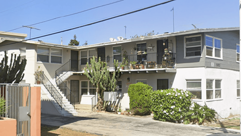 A grey and white two story house with a cactus in front.