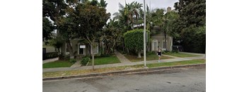 A person is walking on the sidewalk in front of a house.