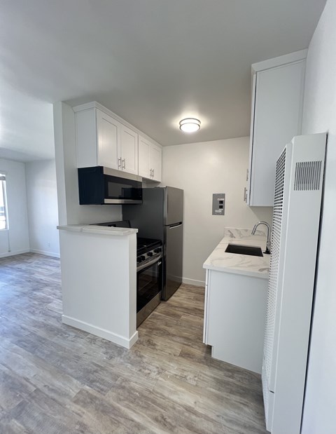A kitchen with a white fridge, black oven, and microwave.