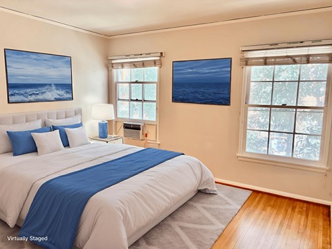 A bedroom with a large bed and two pictures on the wall.