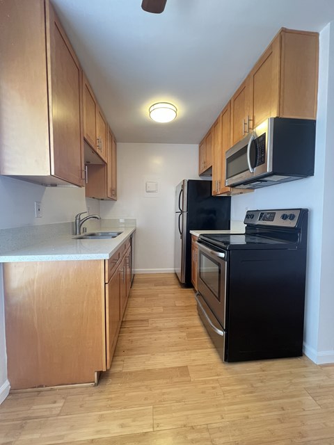 A kitchen with black appliances and wooden cabinets.