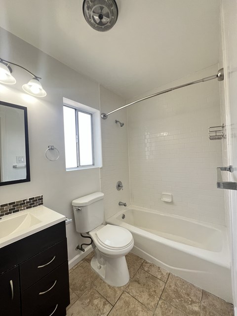 A white toilet sits next to a white bathtub in a bathroom.