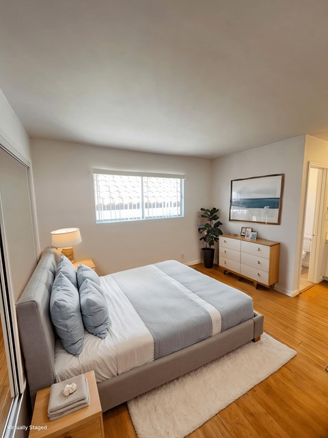 A bedroom with a bed, nightstand, and window.
