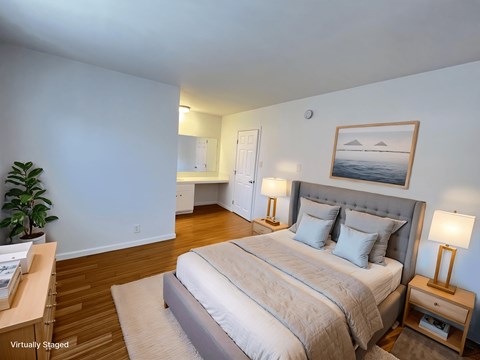A bedroom with a large bed and a painting on the wall.