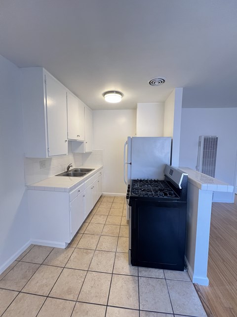 A kitchen with white cabinets and a black fridge.