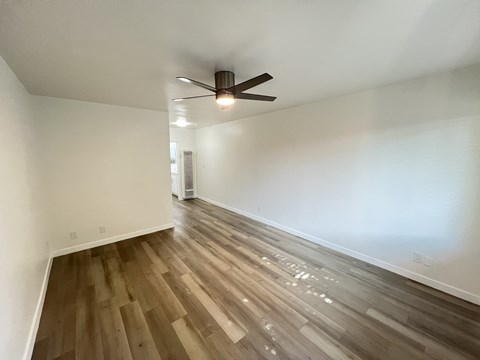 A room with a ceiling fan and wooden flooring.