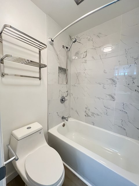 A white toilet sits next to a bathtub in a bathroom.