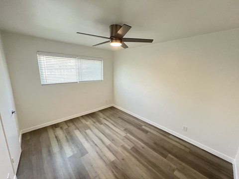 A room with a ceiling fan and a window with blinds.