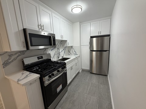 A kitchen with a stove, microwave, and refrigerator.