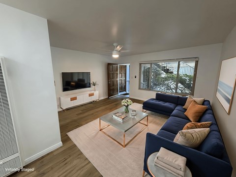 A living room with a blue couch and a glass coffee table.
