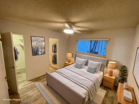 A bedroom with a bed, nightstands, and a ceiling fan.