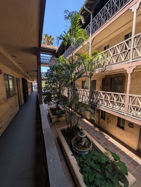 A balcony with a railing and a tree in a planter box.