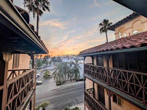 A view from a balcony overlooking a parking lot and palm trees.