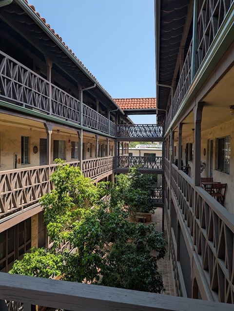 A balcony with a green railing overlooks a courtyard.