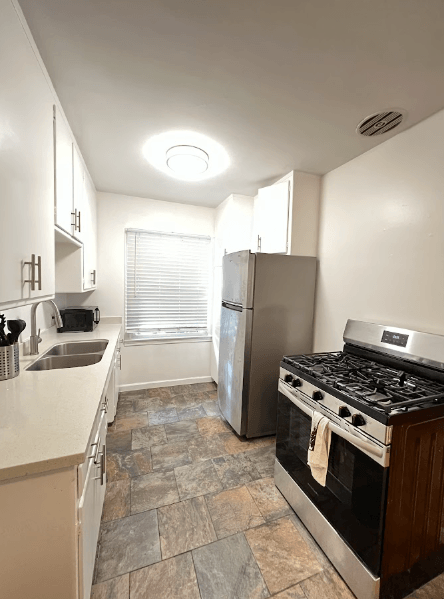 A kitchen with a stove, sink, and refrigerator.