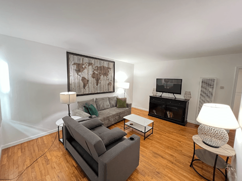 A living room with a grey couch, a coffee table, and a world map on the wall.
