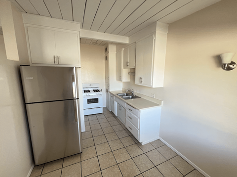 A kitchen with white cabinets and a stainless steel refrigerator.