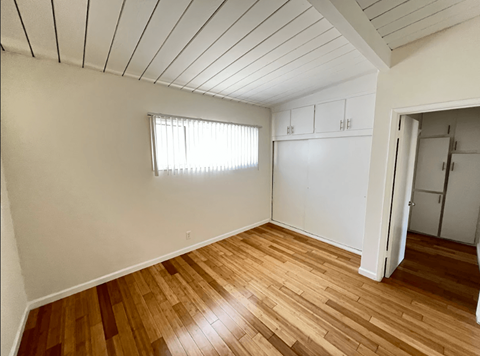 A room with wooden floors and a window with blinds.