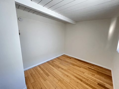 A room with wooden flooring and white walls.