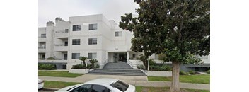 A white building with a tree in front of it.