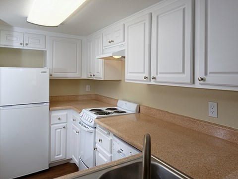 A kitchen with white cabinets and a white fridge.