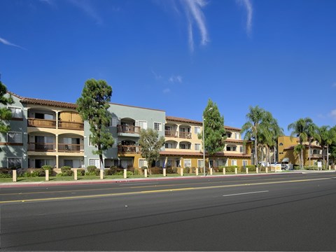 A row of apartment buildings with trees in front of them.