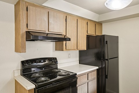 A kitchen with a black stove and black refrigerator.
