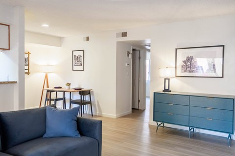 A blue couch sits in a living room with a wooden floor and white walls.