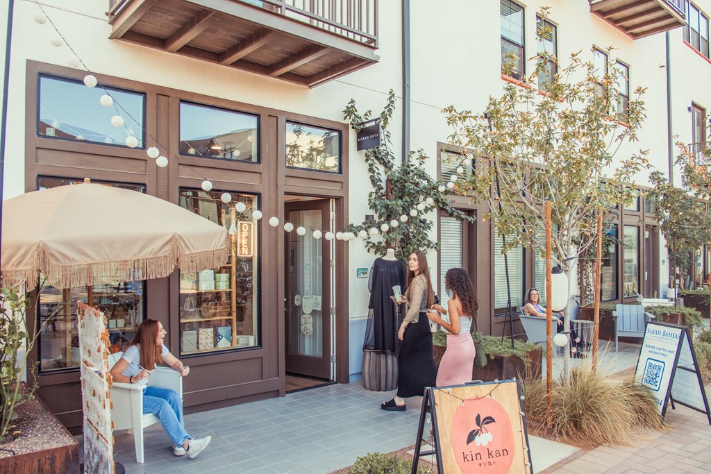 A woman is sitting on a chair outside a building with a sign that reads "kin kan".