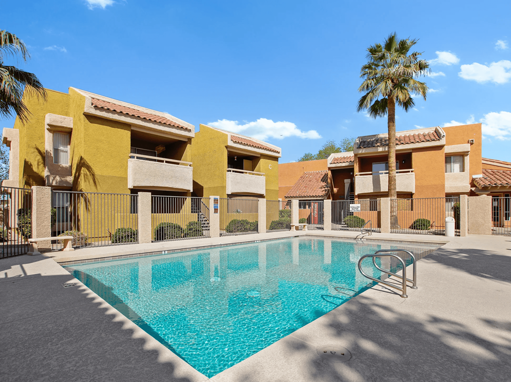 A swimming pool in front of a building with a palm tree.