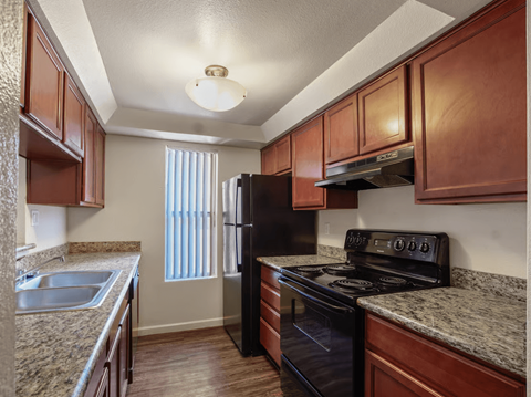 A kitchen with brown cabinets and a black stove top oven.