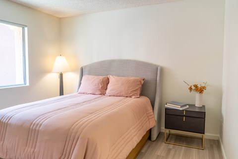 A bedroom with a bed, nightstand, and lamp.