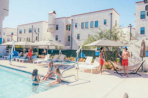 A group of people are enjoying a sunny day by the pool.