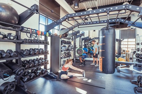 A gym with a woman exercising and a man watching her.