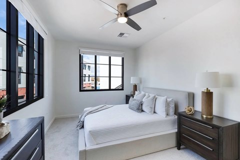 A bedroom with a bed, nightstand, and a ceiling fan.