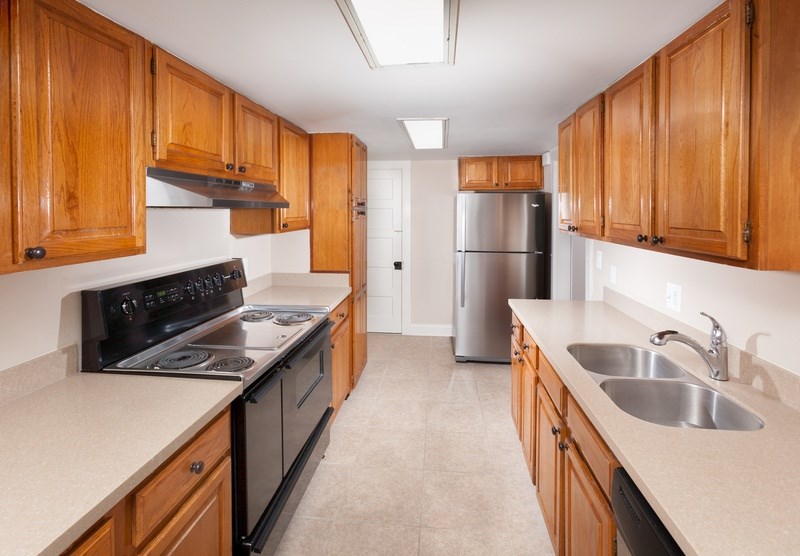 A kitchen with wooden cabinets and a stainless steel refrigerator.