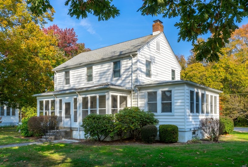 A white house with a grey roof and a chimney.
