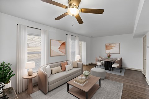 A living room with a beige couch, a brown coffee table, and a ceiling fan.