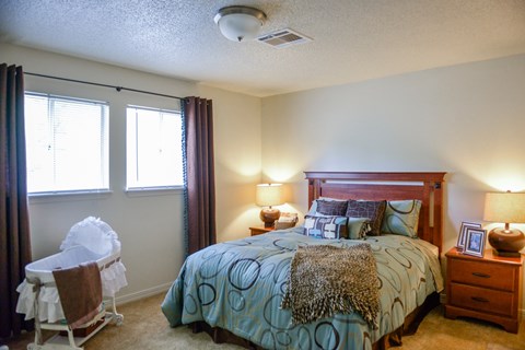 A bedroom with a bed, nightstand, and chair.