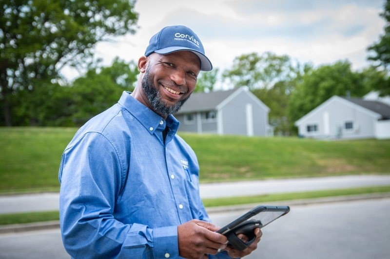 A man in a blue shirt and cap is holding a tablet.
