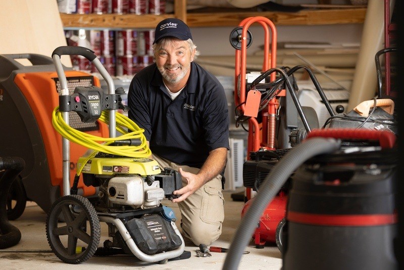 A man in a blue shirt is working on a yellow and black machine.