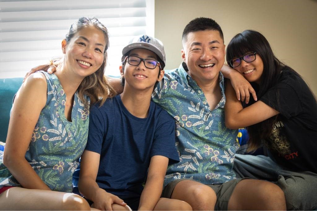 Four people wearing blue shirts are sitting on a couch.