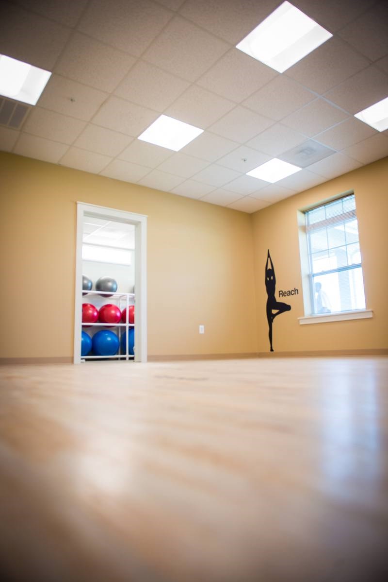 A room with a window, a shelf with exercise balls and a yoga figure.