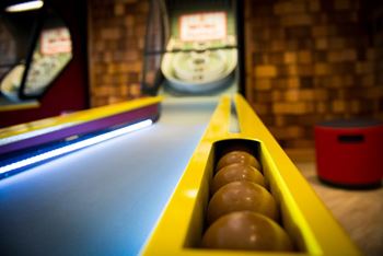 A pool table with a yellow rack and red trash can in the background.