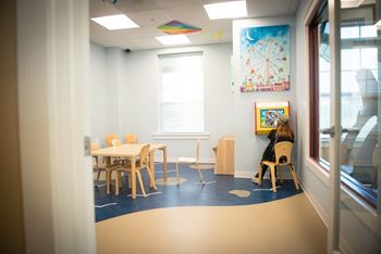 A child is sitting at a table in a brightly lit room.