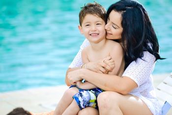 A woman is hugging a boy by the pool.