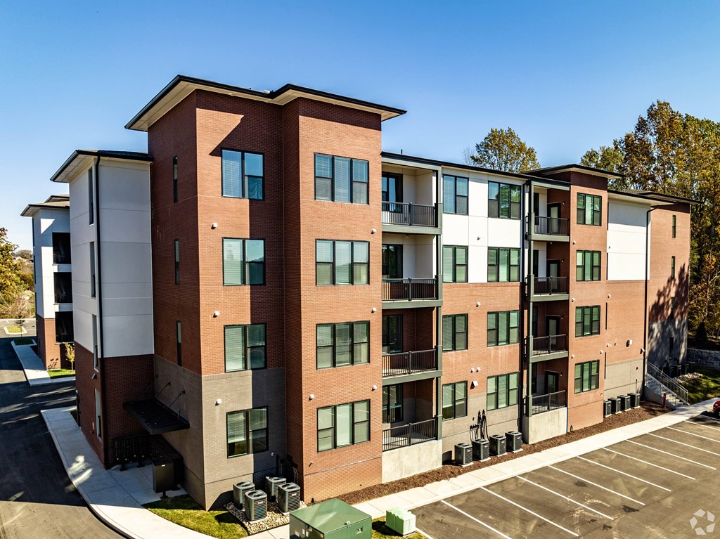 A large apartment building with a parking lot in front.
