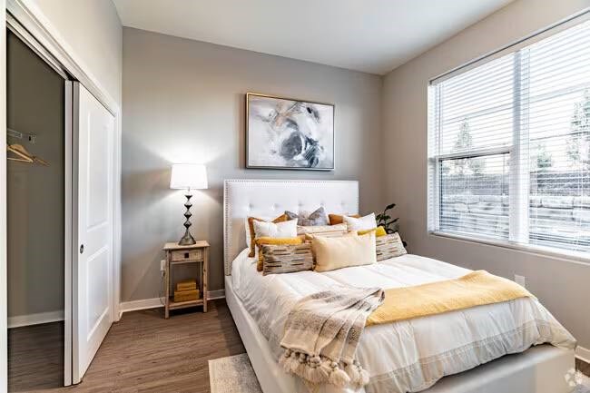 A bedroom with a bed, a nightstand, and a painting on the wall.