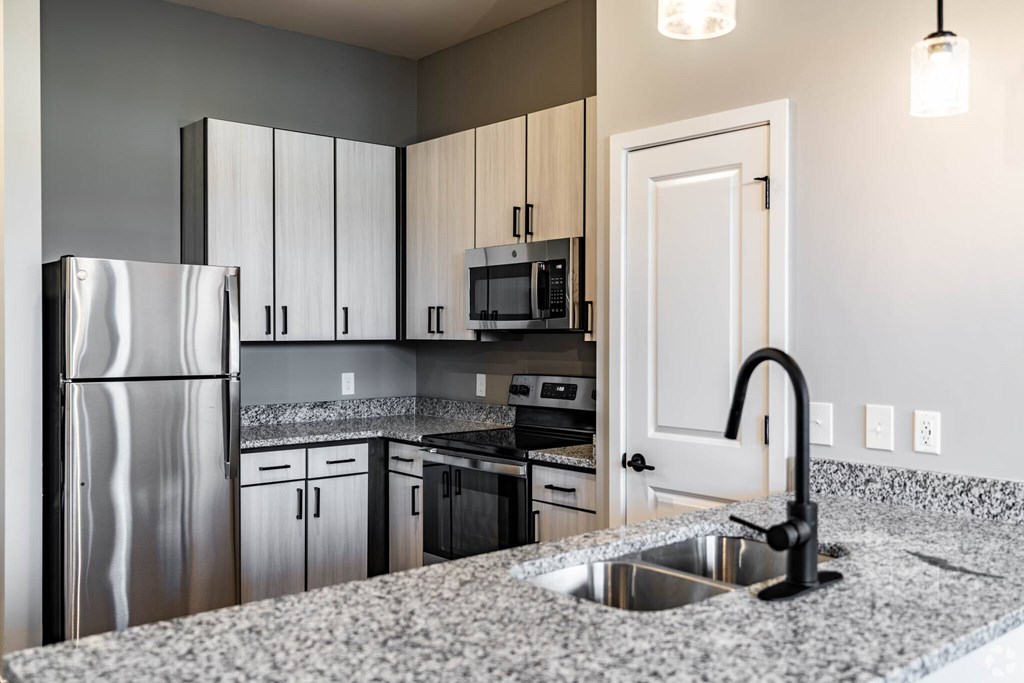 A modern kitchen with a granite countertop and stainless steel appliances.