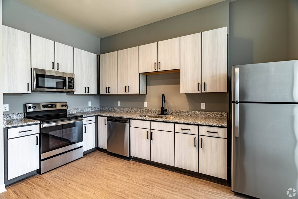 A kitchen with a refrigerator, oven, and microwave.